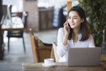 Китаянка разговаривает по телефону в кафе — стоковое фото