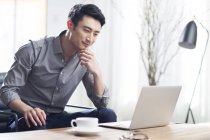 Азиатский человек работает с ноутбуком в офисе — стоковое фото