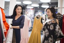 Chinoise amis choisir entre des robes dans le magasin de vêtements — Photo de stock