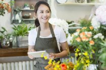 Female chinese florist using digital tablet in shop — Stock Photo