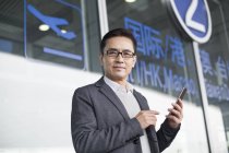 Asiático homem segurando smartphone no aeroporto — Fotografia de Stock