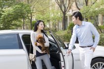 Asiático pareja llegar fuera de coche con mascota perro - foto de stock
