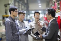 Chinese businessman and engineers talking at factory — Stock Photo