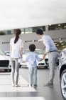 Famille chinoise dans le concessionnaire automobile showroom pointant sur les voitures — Photo de stock