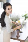Femme chinoise arrangeant des fleurs à la maison — Photo de stock