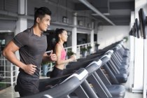 Chinesisches Paar läuft in Turnhalle auf Laufbändern — Stockfoto