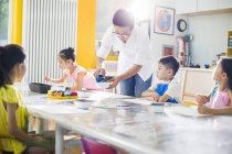 Chinese children painting in art class with teacher — Stock Photo