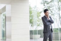 Empresário asiático em pé na frente da porta de vidro — Fotografia de Stock