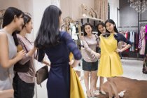 Chinese female friends trying on dress in clothing store — Stock Photo