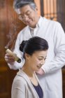 Зрелый китайский врач дает женщине moxibustion — стоковое фото