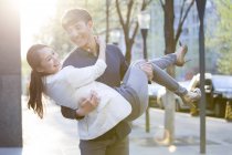 Chinese man carrying girlfriend in arms on street — Stock Photo