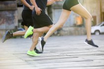 Обрізаний вид на ноги бігунів, що біжать на вулиці — стокове фото