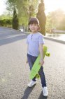 Chinese boy posing with skateboard on road — Stock Photo