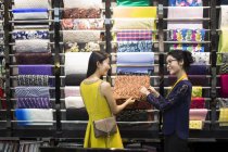 Chinese fashion designer helping customer choosing fabric swatch — Stock Photo