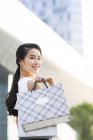 Femme asiatique posant dans la rue avec des sacs à provisions — Photo de stock