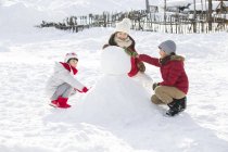 Китайские дети делают снеговика на открытом воздухе — стоковое фото