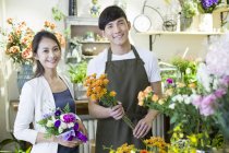 Floristería masculina china y cliente en tienda de flores - foto de stock