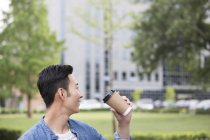 Chinese man drinking coffee from disposable cup — Stock Photo