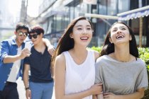 Chinese female friends walking with men on street — Stock Photo