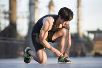 Asiatico jogger legatura shoelaces su strada — Foto stock