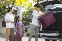 Chinese family packing suitcases in car trunk — Stock Photo