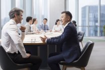 Equipo empresarial chino que se reúne con socios extranjeros en la sala de juntas - foto de stock