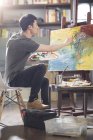 Pintor masculino asiático trabajando en estudio de arte - foto de stock