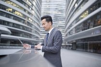 Empresário asiático usando laptop na rua — Fotografia de Stock