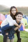 Chinese couple riding piggyback at festival camping — Stock Photo