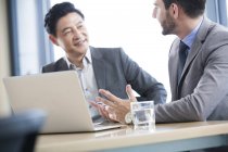 Gli uomini d'affari discutono il lavoro con il computer portatile nella sala riunioni — Foto stock