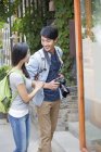 Chinese couple standing on street with camera — Stock Photo