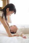 Menina chinesa brincando com menino na cama — Fotografia de Stock