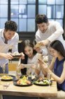 Asian friends taking photos of food while dinner in restaurant — Stock Photo