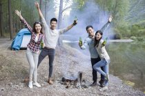 Chinese friends standing at campfire with beer — Stock Photo