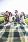 Amigos chinos sentados en manta en el festival de música - foto de stock