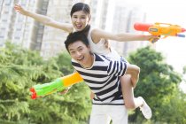 Joven adulto chino pareja jugando con squirt armas - foto de stock