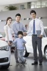 Chinese family with car keys in showroom with car seller — Stock Photo