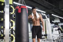 Chinese man resting with towel at gym — Stock Photo