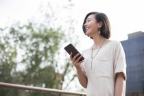 Китайська Жінка тримає смартфон в місті — стокове фото
