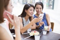 Amigos do sexo feminino usando smartphones no café da calçada — Fotografia de Stock