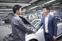 Chinês mecânico de automóveis e proprietário do carro apertando as mãos — Fotografia de Stock