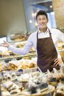 Asiatique homme debout au comptoir de boulangerie — Photo de stock