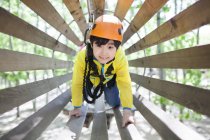 Ragazzo cinese in albero top parco avventura tubo di legno — Foto stock
