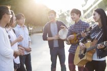 Chinese friends performing music on street — Stock Photo