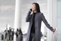 Mulher asiática falando no telefone no aeroporto — Fotografia de Stock
