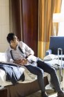 Hombre de negocios chino descansando en la habitación de hotel - foto de stock