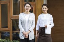 Chinesischer Restaurantbesitzer und Kellnerin stehen vor Tür — Stockfoto