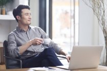Asiatischer Mann trinkt Kaffee im Büro — Stockfoto