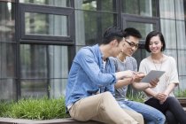 Equipe de negócios casual chinesa conversando com tablet digital na cidade — Fotografia de Stock