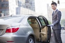 Chinese chauffeur opening car door — Stock Photo